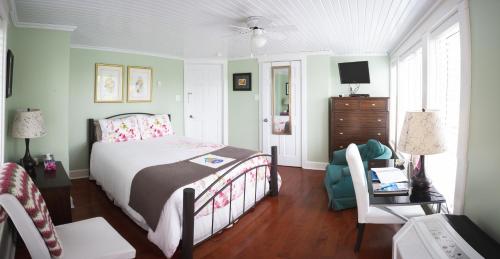 um quarto com uma cama, uma cadeira e uma televisão em Abbie's Garden Bed & Breakfast em Grand Bank