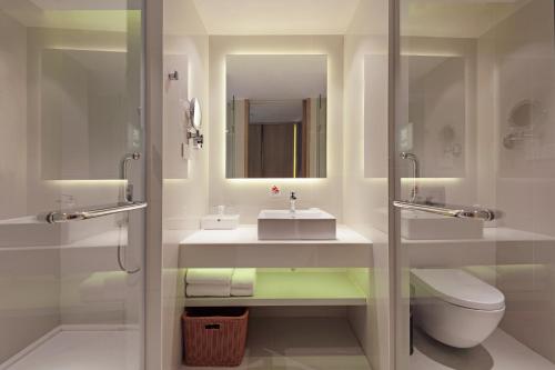a bathroom with a sink and a toilet and a mirror at Haikou Meilan International Airport Hotel in Haikou
