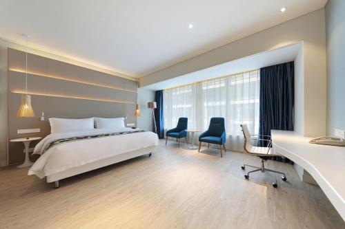 a hotel room with a bed and a desk and chairs at Haikou Meilan International Airport Hotel in Haikou