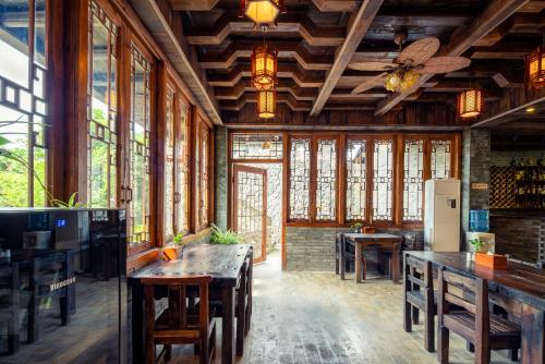 a dining room with tables and chairs and windows at Yangshuo River Lodge Hotel in Yangshuo