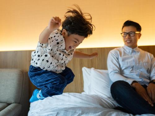 a young boy jumping on top of a bed at Hotel Flags Isahaya Nagasaki in Isahaya