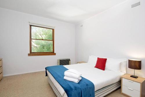 a bedroom with a bed with white sheets and red pillows at HIGH5NS - Haven on High in Sydney