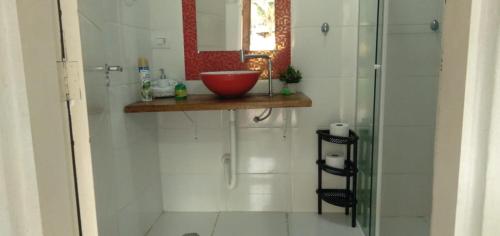 La salle de bains est pourvue d'une douche avec un bol rouge sur un comptoir. dans l'établissement Recanto dos Pássaros, à Ilhabela