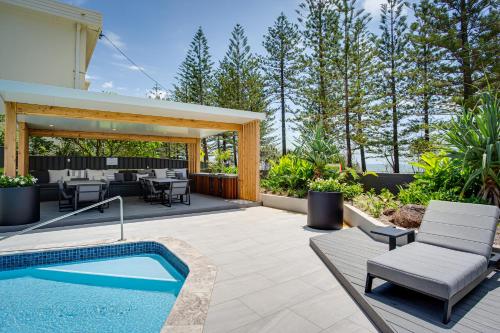 patio trasero con piscina y patio con mesa y sillas en Burleigh Esplanade Apartments, en Gold Coast