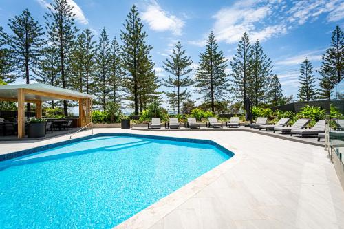 a pool with a pool table and chairs in it at Burleigh Esplanade Apartments in Gold Coast