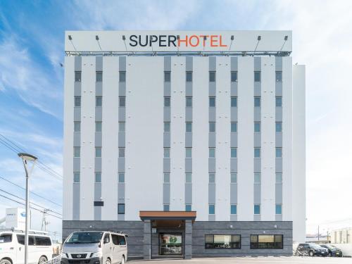 a hotel with cars parked in front of it at Super Hotel Sendai Airport Inter in Natori