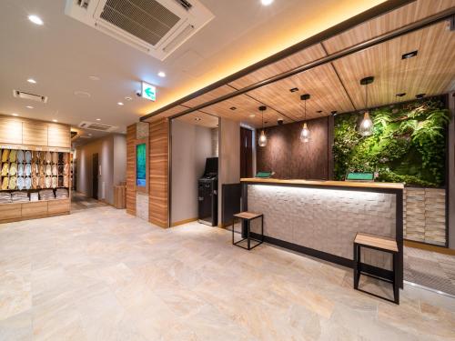 a lobby with a bar with a plant on the wall at Super Hotel Sendai Airport Inter in Natori