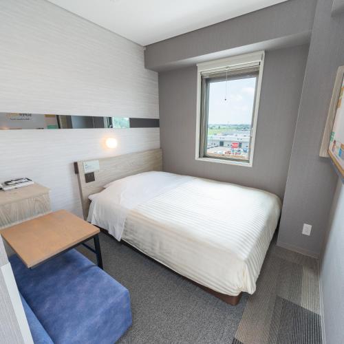 a small bedroom with a bed and a window at Super Hotel Sendai Airport Inter in Natori
