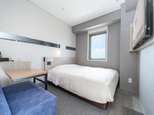 a small bedroom with a bed and a table at Super Hotel Sendai Airport Inter in Natori
