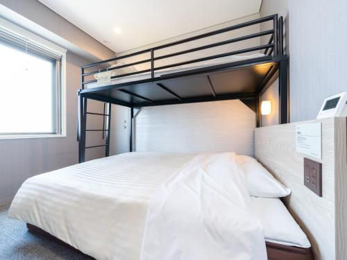 a bedroom with a bunk bed with white bedding at Super Hotel Sendai Airport Inter in Natori