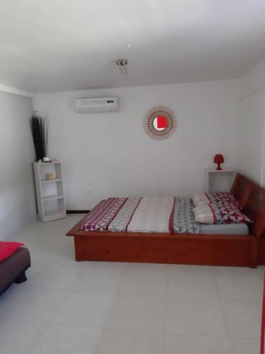 a bedroom with a bed and a clock on the wall at Appartement dans Villa avec jardin et piscine pour détente et évasion in Montjoly