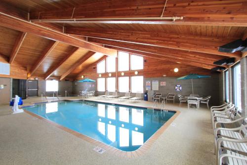 a large swimming pool in a building with tables and chairs at AmericInn by Wyndham Cedar Rapids Airport in Cedar Rapids