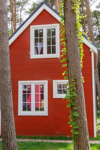 a red house with white windows between two trees at Pinia in Pobierowo