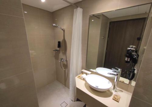 a bathroom with a shower and a sink and a mirror at Belmont Hotel Boracay near Newcoast Beach in Boracay