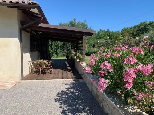 a porch with a bench and pink flowers at Podere Battegone in Menestrello
