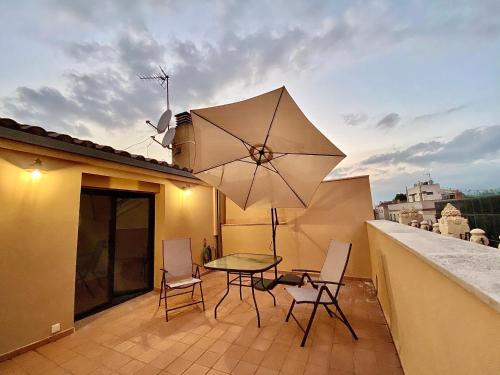 eine Terrasse mit einem Tisch, Stühlen und einem Sonnenschirm in der Unterkunft Spiral Stairs Duplex in Figueres