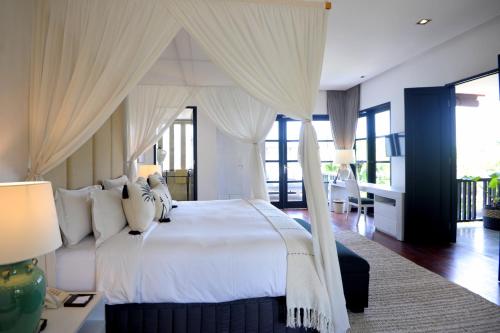 a bedroom with a large white bed with curtains at Akara Villa in Seminyak