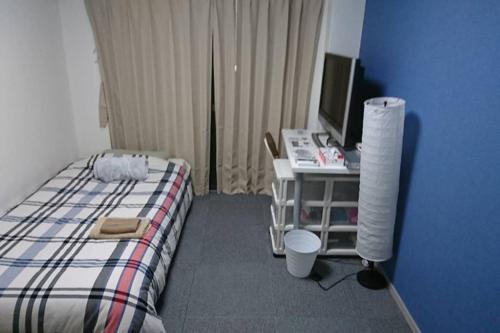 a bedroom with a bed and a desk with a computer at エバグリーンヴィラ太秦203さくら in Sagano