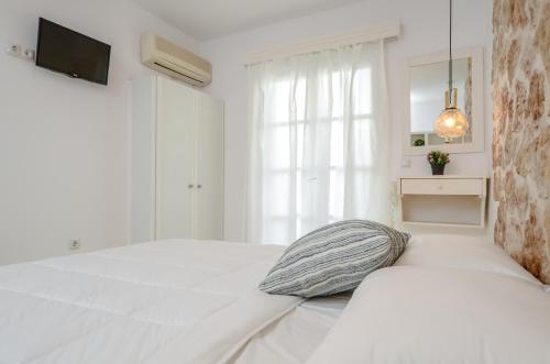 a white bedroom with a bed and a window at simos luxury apartments in Naxos Chora