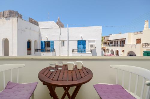 a wooden table on a balcony with purple chairs at simos luxury apartments in Naxos Chora