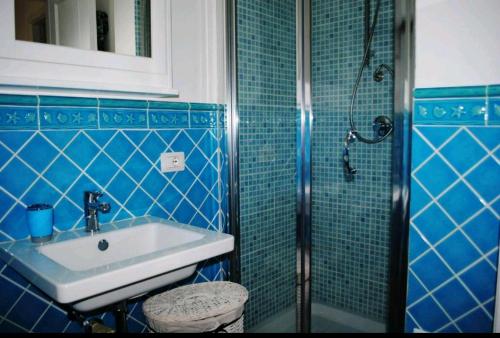 ポルト・ロトンドにあるPorto Rotondoの青いタイル張りのバスルーム(シンク、シャワー付)