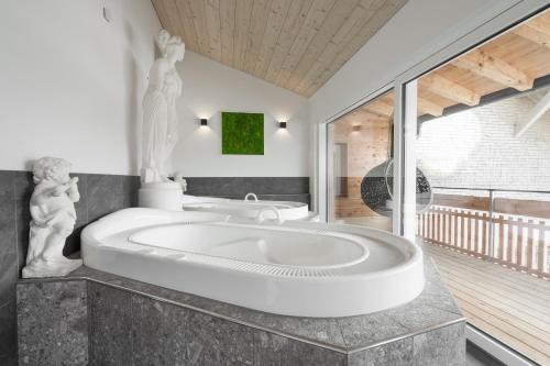 uma casa de banho com uma grande banheira com uma estátua em Kienle - das Kräuterhotel em Balderschwang