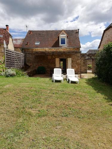 dos sillas blancas sentadas en el patio de una casa en gite climatisé au calme à la campagne, en Branceilles