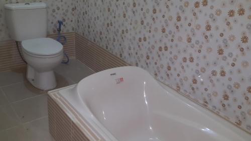 a bathroom with a toilet and a bath tub at Jepun Bali hotel negara in Negara