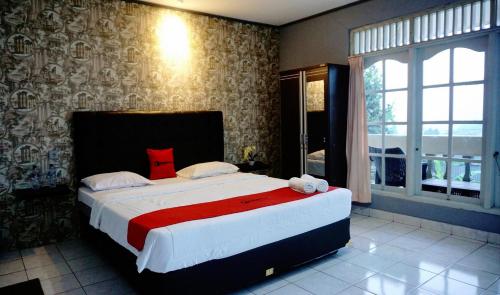 a bedroom with a large bed with a red blanket at Residences by RedDoorz near Taman Safari in Bogor