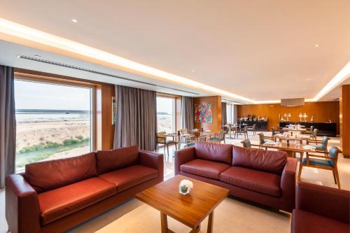 a hotel lobby with couches and tables and a restaurant at Crowne Plaza Muscat OCEC by IHG in Muscat