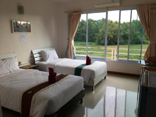 a bedroom with two beds and a large window at Siriburi Resort in Khanom