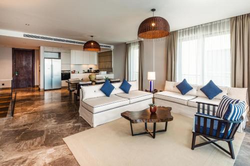 Kaya Palazzo Resort & Residences Le Chic Bodrum في بودروم: غرفة معيشة مع أريكة بيضاء ووسائد زرقاء