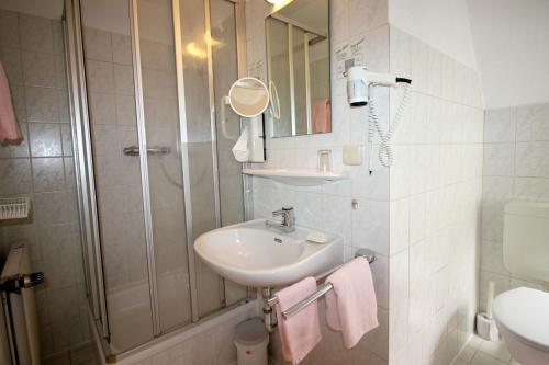 a white bathroom with a sink and a shower at Hotel-Garni Haus Johanna in Einbeck