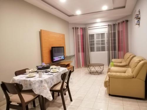 a living room with a table and a couch and a television at Green Hill Resort Tanah Rata 3R2B WiFi in Tanah Rata