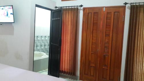 uma casa de banho com um chuveiro e uma porta de madeira em Jepun Bali hotel negara em Negara
