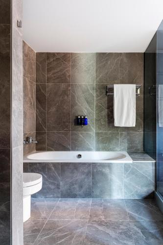 a bathroom with a tub and a toilet at Radisson Blu Hotel, Madrid Prado in Madrid