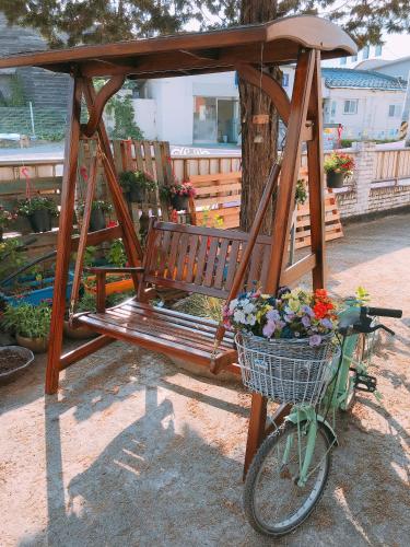 a bike parked next to a wooden bench with a basket of flowers at Jarasum Guest House in Gapyeong