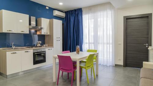 a kitchen with a white table and colorful chairs at Residence Palazzo dei Delfini by RECEPTIO in Catania