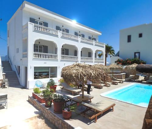 a large white building with a swimming pool and chairs at Avraki in Kamari