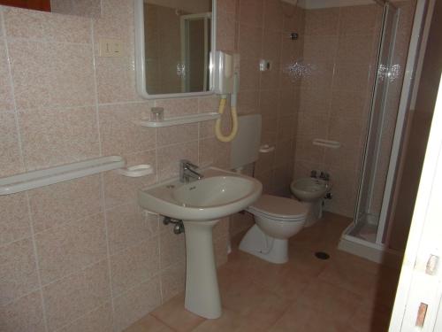 a bathroom with a sink and a toilet and a phone at Hotel Villa Nettuno in Marina di Campo