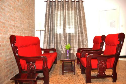 a living room with two chairs and a red couch at Hotel 198 Negombo in Negombo
