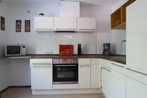 cocina blanca con armarios blancos y horno en Ferienwohnung Sahi, en Celle
