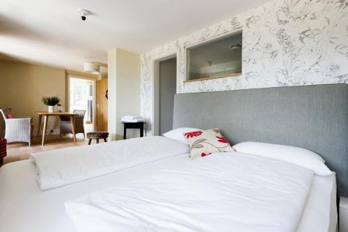 a bedroom with a white bed with a tv on the wall at Berghaus Freiburg - Appartement Hotel auf dem Schauinsland in Oberried
