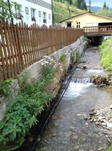 a wooden fence next to a stream of water at Casa Craciun Ciocanesti in Ciocăneşti