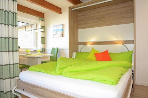 sypialnia z łóżkiem z zieloną pościelą i biurkiem w obiekcie Dünenhof DD3-051 Dünenhof w mieście Heiligenhafen