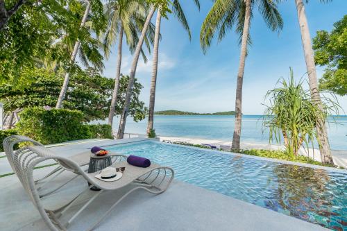 a resort pool with a table and a chair at La Vida Samui in Chaweng