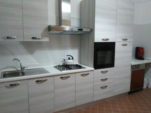 a kitchen with white cabinets and a stove top oven at B&B Piazza San Benedetto in Militello in Val di Catania