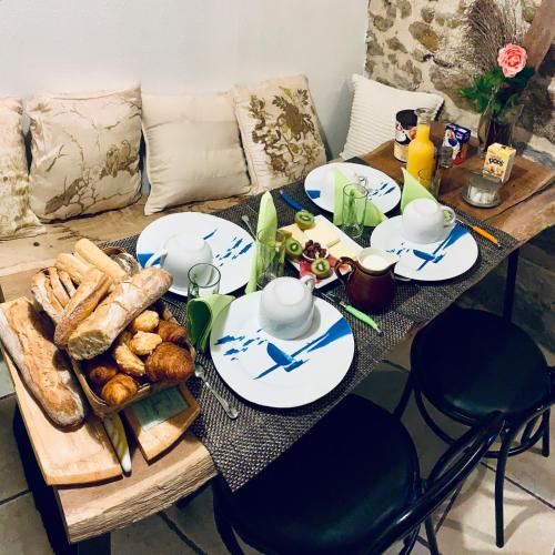 een tafel met brood en kopjes en borden met voedsel bij Chambres d'Hôtes du Manoir du Haut Salmon in Saint-Malo