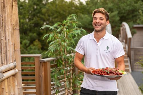 a man is holding a plate of strawberries at Treetop Spa Hangout & Hotel in Gothenburg