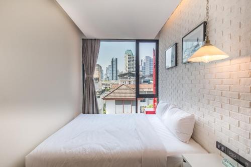 a bedroom with a white bed and a large window at Sleep Box Sukhumvit 22 in Bangkok